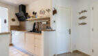 Modern kitchen of the sea view villa in Cala Murada with white fronts, wooden worktop and black extractor hood.