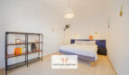 Helles Schlafzimmer mit Doppelbett, blauem Kopfteil, Bücherregal und Deckenlampe im Stadthaus Manacor