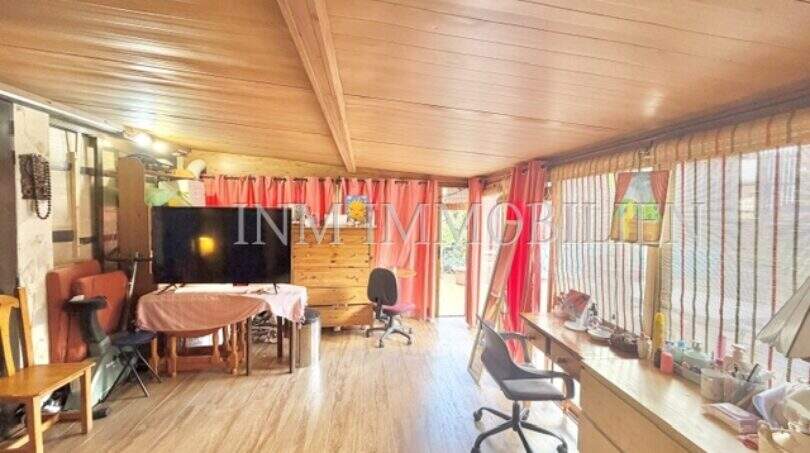 Wohnzimmer mit Holzdecke, Laminatboden, TV-Bereich und Schreibtisch mit Blick zur Terrasse