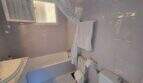 Bathroom of the finca in Cala Millor with bathtub, shower curtain, radiator and tiled walls