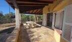Covered terrace of the finca in Cala Millor with wooden beam ceiling, natural stone furniture and garden view
