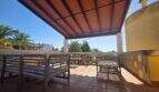 Covered terrace with wooden furniture and view of palms of the finca in Cala Millor, Sant Llorenç