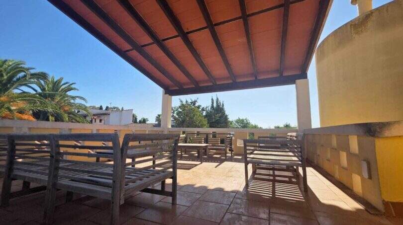 Covered terrace with wooden furniture and view of palms of the finca in Cala Millor, Sant Llorenç