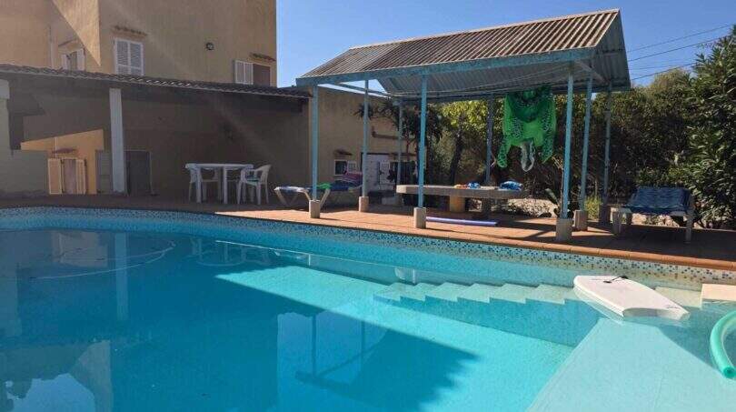 Outdoor pool of the finca in Cala Millor with terrace, pergola and Mediterranean residential building in the background