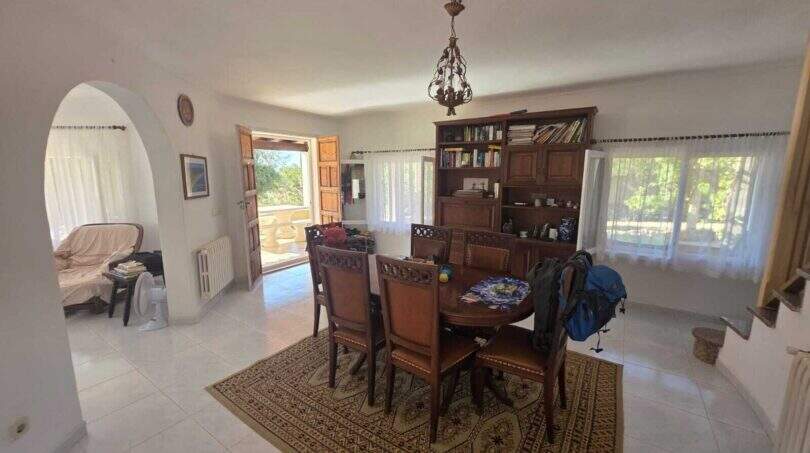 Bright dining room of the finca with antique wooden table, arched passage and terrace door to the garden.
