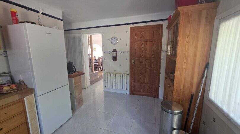 Kitchen of the finca in Cala Millor with tiled floor, refrigerator, wooden door and wall tile decor