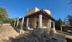 Exterior view of the finca in Cala Millor with covered terrace, white columns and yellow facade.