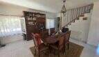 Dining room of the finca in Cala Millor with round wooden table, bookshelf and staircase to the upper floor.