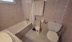 Bathroom of the finca in Cala Millor with bathtub, toilet, shower curtain and light tile floor