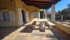 Covered terrace of the finca in Cala Millor with stone table, wooden beam ceiling and Mediterranean flair.