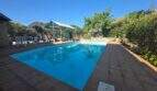 Rectangular pool with blue water, terrace area and sun protection at finca in Cala Millor