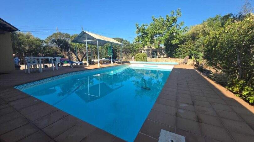 Rectangular pool with blue water, terrace area and sun protection at finca in Cala Millor