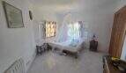 Bright bedroom of the finca in Cala Millor with mosquito net, tile floor and two windows.