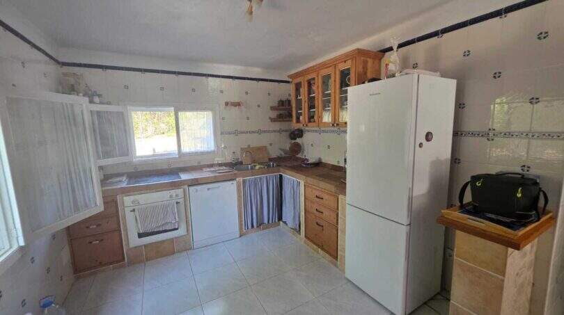 Rustic kitchen of the finca in Cala Millor with wooden cabinets, tiles and white built-in appliances