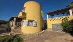 Exterior view of the finca in Cala Millor with distinctive yellow round tower facade, garage and covered terrace.