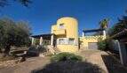 Exterior view of the yellow finca in Cala Millor with distinctive round tower, terrace and Mediterranean vegetation.