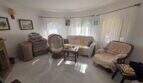 Living room of the finca in Cala Millor with fireplace, rattan armchair, sofa and large windows with curtains.