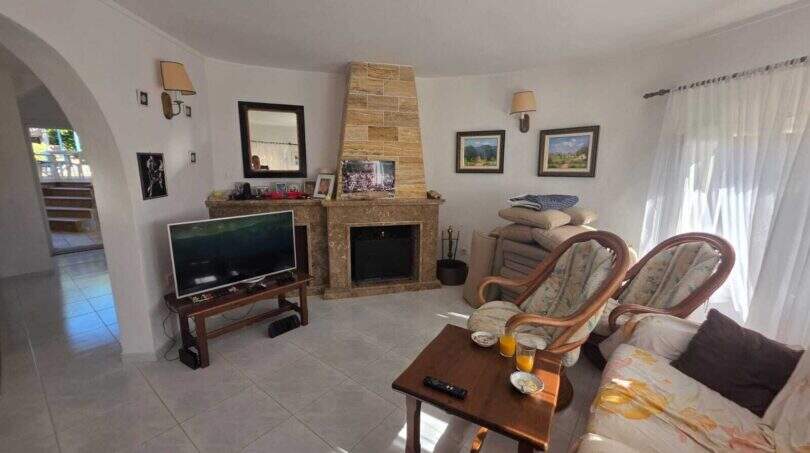 Bright living room of the finca in Cala Millor with fireplace, rattan chairs and sofa
