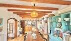Comedor rústico con techo de vigas de madera, larga mesa de comedor y aparador vintage turquesa en casa mediterránea Sa Ràpita