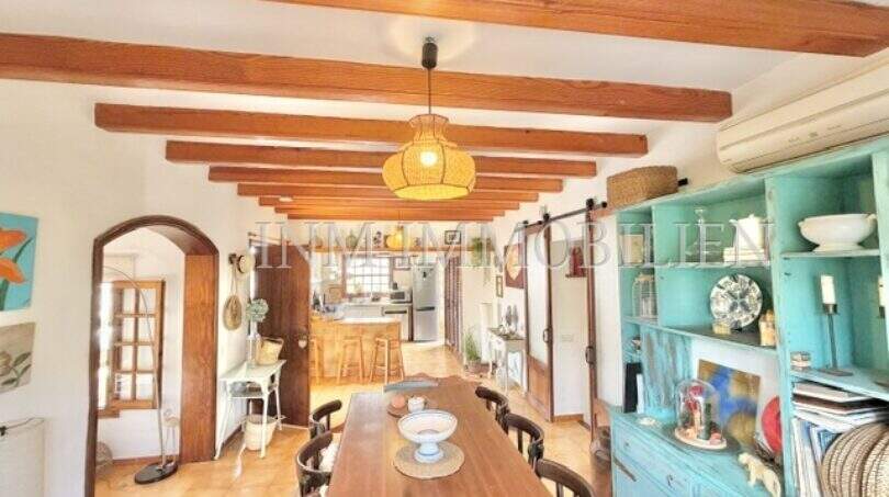 Comedor rústico con techo de vigas de madera, larga mesa de comedor y aparador vintage turquesa en casa mediterránea Sa Ràpita