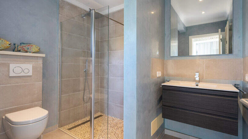 Modern bathroom of the sea view villa in Cala Murada with glass shower, wall toilet and elegant washbasin.