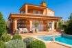 Außenansicht Villa Sa Coma mit Pool, Terrasse, Loungemöbeln und mediterranem Garten unter blauem Himmel.