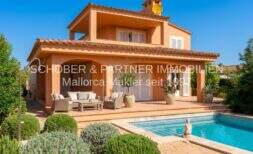 Außenansicht Villa Sa Coma mit Pool, Terrasse, Loungemöbeln und mediterranem Garten unter blauem Himmel.