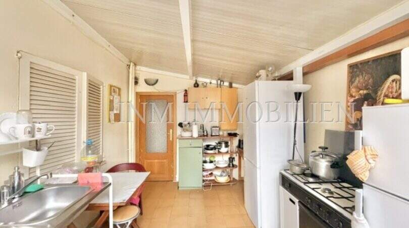 Schmale Küche der Wohnung in Palma-City mit Gasherd, Kühlschrank, Spüle und Esstisch.