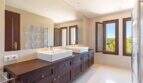 Exclusive finca bathroom with double vanity, dark wooden base cabinet and nature view through wooden window in Felanitx.