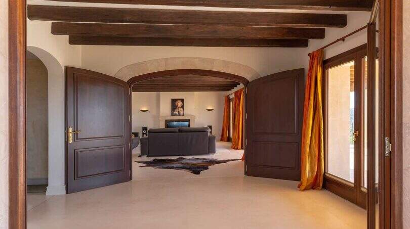 Elegant entrance area of Felanitx finca with wooden beam ceiling, round arches and dark mahogany doors