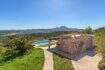 Exclusive finca in Felanitx: natural stone building with pool, pergola, palm tree and panoramic view of mountains and valley.