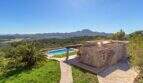 Exclusive finca in Felanitx: natural stone building with pool, pergola, palm tree and panoramic view of mountains and valley.