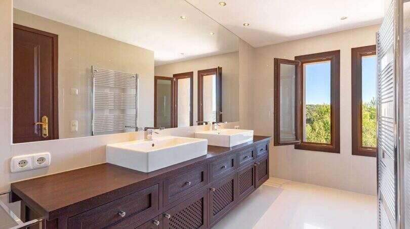 Exclusive bathroom of Felanitx finca with double sink, dark wooden base cabinet and large wall mirror