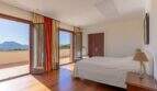 Bright bedroom of Felanitx finca with wooden floor, double bed and panoramic doors with mountain view.