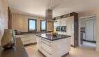 Modern fitted kitchen with cooking island, extractor hood and sea view from window in exclusive Felanitx finca