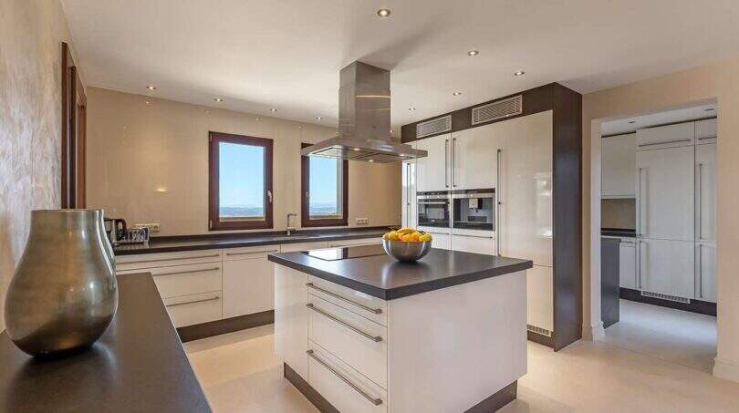 Modern fitted kitchen with cooking island, extractor hood and sea view from window in exclusive Felanitx finca