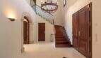 Elegant entrance area of the finca in Felanitx with wooden staircase, chandelier and dark wooden doors