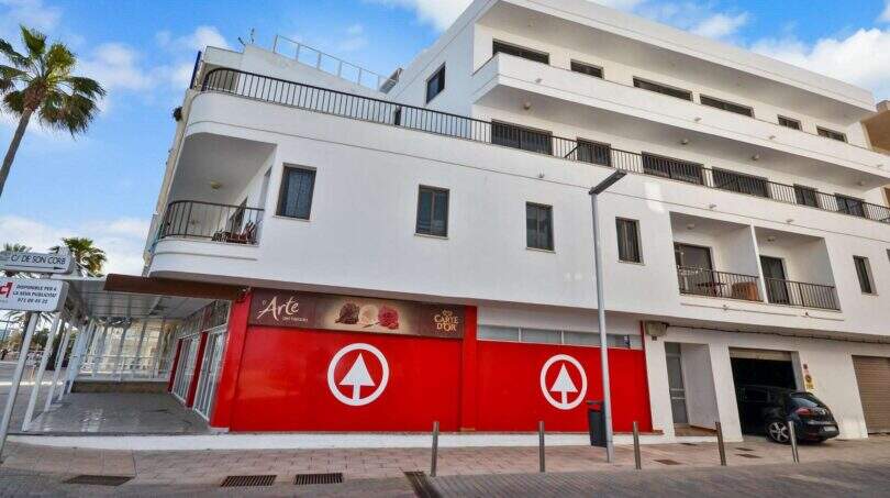 Außenansicht Investitionsobjekt Cala Millor: weißes Mehrfamilienhaus in erster Meereslinie mit Balkonen und Geschäftsfläche.