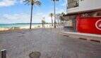 Strandpromenade Cala Millor mit Palmen, türkisem Meer und Gewerbelokal in erster Meereslinie