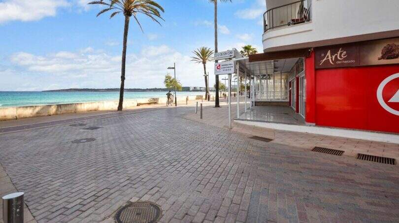 Strandpromenade Cala Millor mit Palmen, türkisem Meer und Gewerbelokal in erster Meereslinie