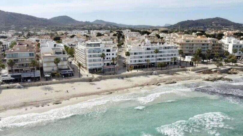 Luftaufnahme Strandpromenade Cala Millor, weiße Gebäude in erster Meereslinie, türkisfarbenes Meer, Bergpanorama