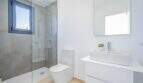 Baño luminoso de la villa nueva en Cala Romántica con ducha de cristal, lavabo moderno e inodoro.