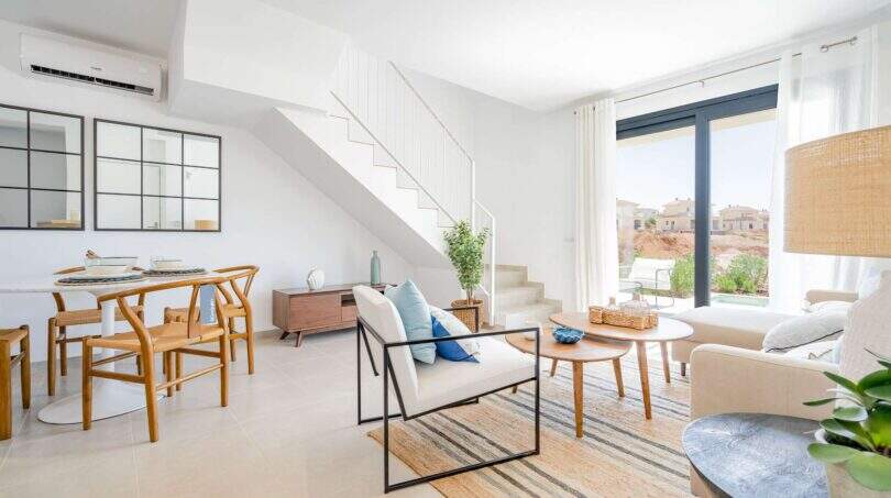 Salón luminoso de la villa nueva en Cala Romántica con escalera, muebles modernos y ventanales panorámicos