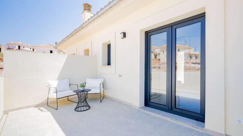Azotea soleada de la villa nueva en Cala Romántica con muebles lounge y puertas correderas de vidrio modernas.