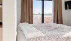 Helles Schlafzimmer der Luxusfinca in Ses Salines mit Doppelbett, Blumendecke und Fenster mit Meerblick.