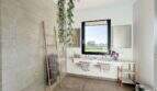 Modernes Badezimmer der Luxusfinca mit Doppelwaschbecken, Glasdusche und Naturblick in Ses Salines