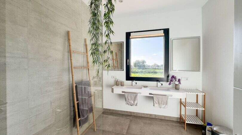Modernes Badezimmer der Luxusfinca mit Doppelwaschbecken, Glasdusche und Naturblick in Ses Salines