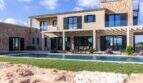 Luxusfinca Ses Salines: Mediterrane Villa mit Pool, Pergola und Natursteinmauer unter blauem Himmel.
