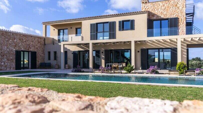 Luxusfinca Ses Salines: Mediterrane Villa mit Pool, Pergola und Natursteinmauer unter blauem Himmel.