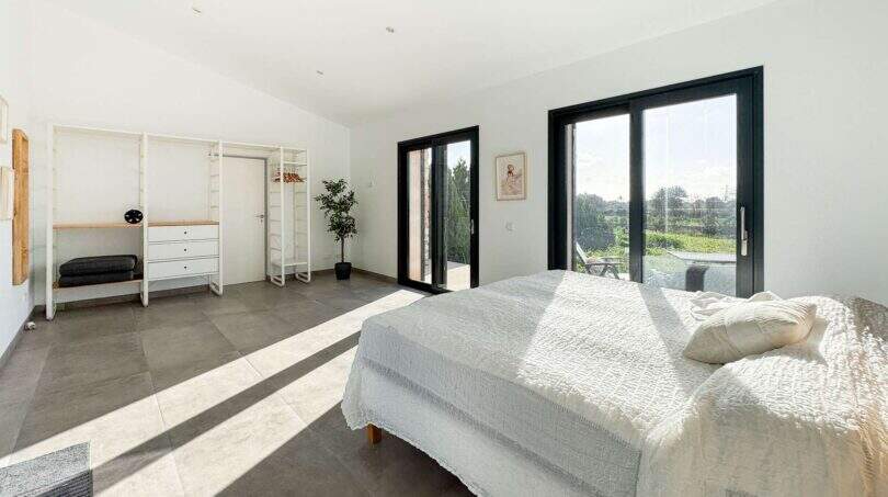 Helles Schlafzimmer der Luxusfinca in Ses Salines mit Terrassenzugang, offenem Kleiderschrank und Gartenblick.